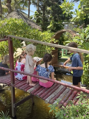 Children on a bamboo bridge over a garden pond in Hoi An