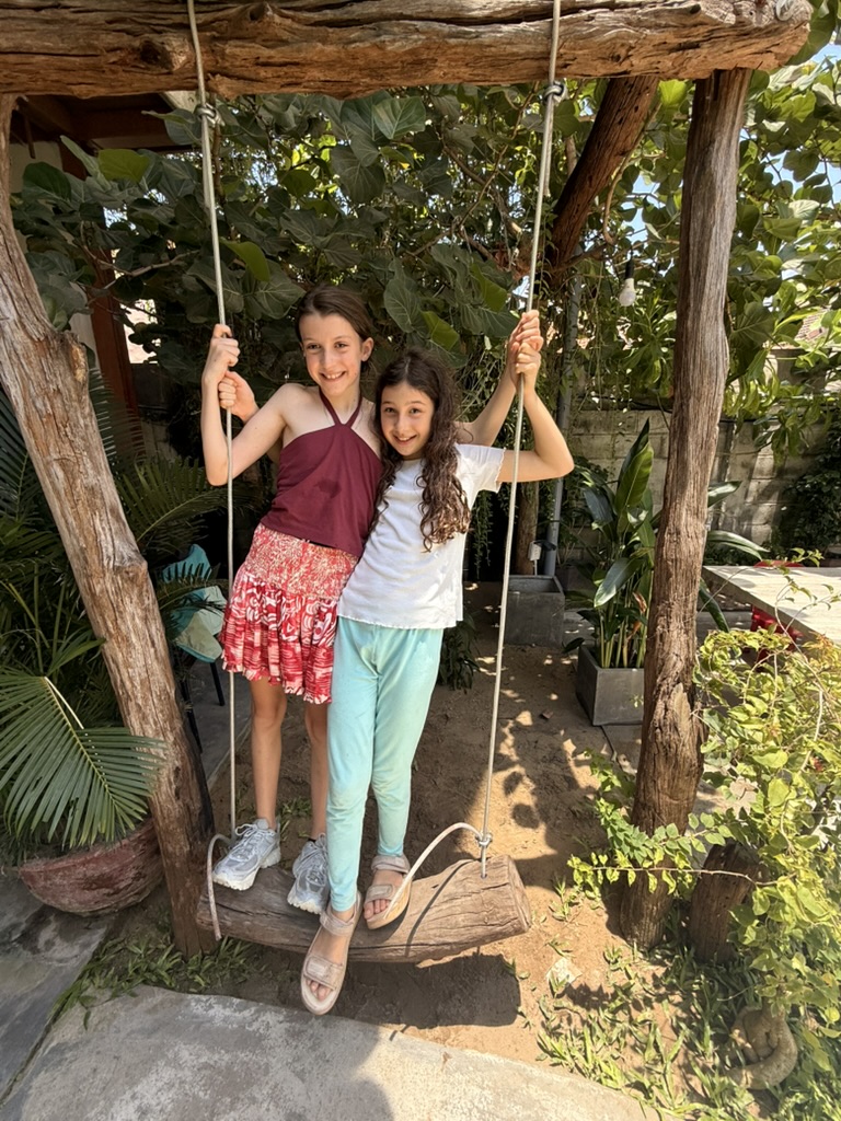 Two children on a garden swing in Hoi An, smiling