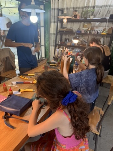 Children working leather with a craftsman in a Hoi An workshop